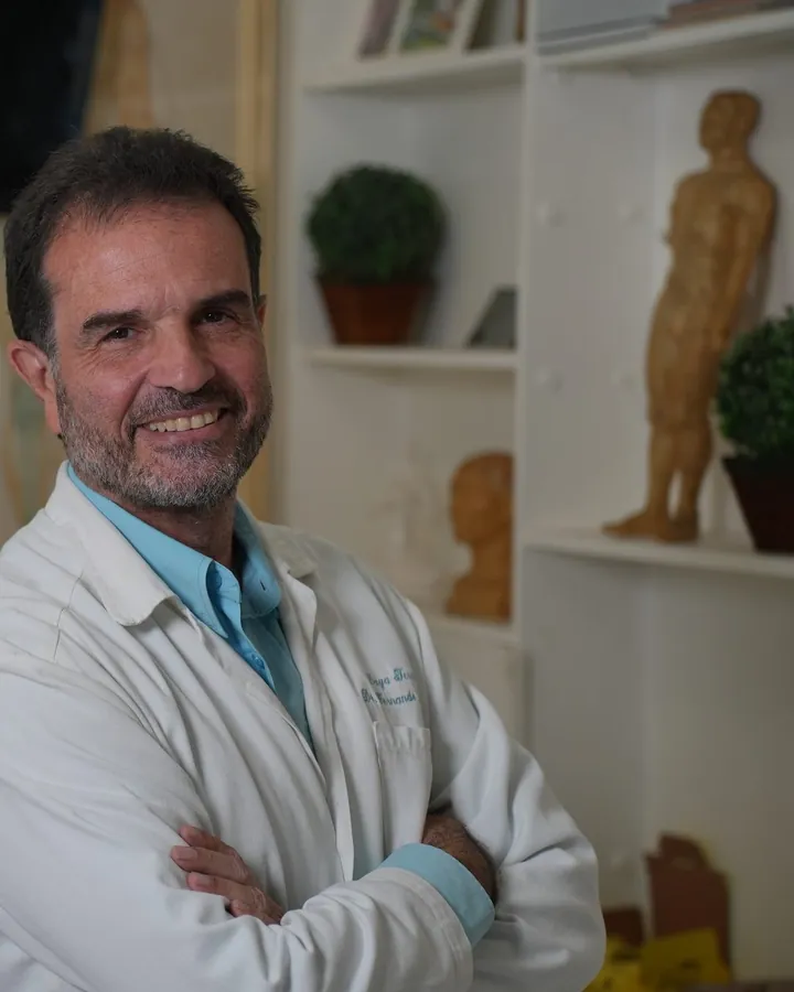 Dr. Fernando Fernandes de jaleco, braços cruzados, no consultório